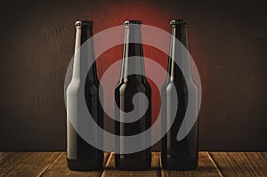 Three black bottle of beer on a red background of a wooden shelf/Three black bottle of beer on a red background of a wooden shelf