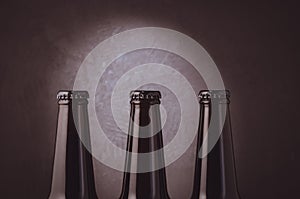 three black bottles of beer on a dark background with light/ three black bottles of beer on a dark background with light