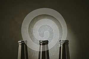 three black bottles of beer on a dark background with light/three black bottles of beer on a dark background with light. Copy