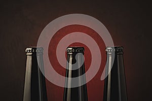 Three black bottles of beer on a dark background with red light/three black bottles of beer on a dark background with red light.