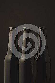 Three black bottles of beer on a dark background/Three black bottles of beer on a dark background, selective focus