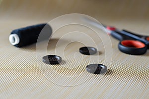 Three black buttons, scissors and threads
