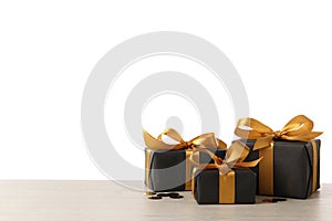 Three black gift boxes on white wooden table. Space for text