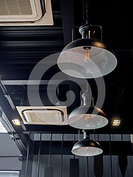 Three black round modern ceiling lights and cassette type air conditioner inside the cafe loft style