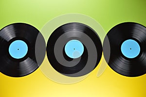 Three black vinyl records on yellow and green