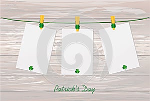 Three blank paper with green clovers hanging on a rope on a wood