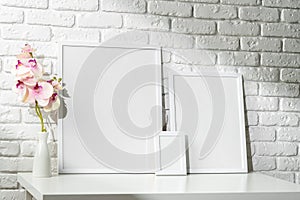 Three Blank Photo Frames on a White Table Against a Brick Wall Background