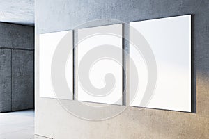 Three blank white canvases on a gray concrete wall in a contemporary gallery setting. 3D Rendering photo