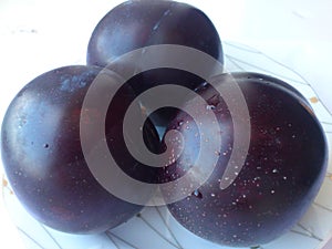 three blue plums on a plate