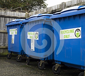 Three blue recycling bins standing in a line