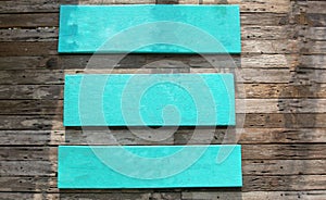 Three blue wooden signs on a wooden wall