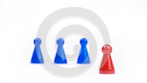 Three blurred blue game pieces as a team and one red sharpened figure as a leader in the foreground. Closeup photo with selective