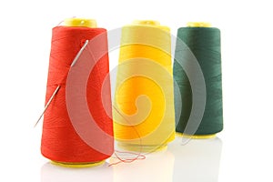 Three bobbins with threads and needle