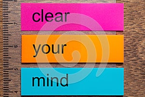 Three bookmark stickers with the word clear your mind on a dark natural wooden table