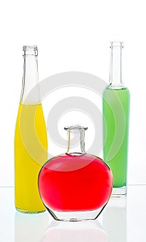 Three bottles with alcohol on a table with the reflecting surfa