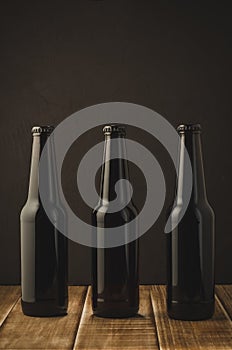 Three bottles of beer on a dark background of a wooden shelf/Three bottles of beer on a dark background of a wooden shelf,