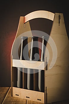 Three bottles of beer in a wooden box/three bottles of beer in a wooden box on a red light background