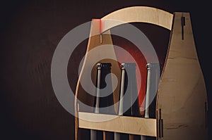 three bottles of beer in a wooden case/beer bottles case on wooden shelf on a red light background. Copyspace
