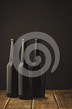 Three bottles of beer of a wooden shelf/Three bottles of beer on a dark background of a wooden shelf