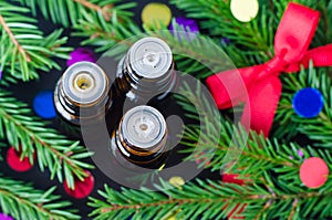 Three bottles of essential oil and fir branches. Christmas aromatherapy and spa concept.