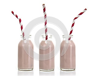 Three Bottles of pink milk with red and white striped straws