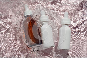 Three bottles with serum in the rippling water on pastel pink