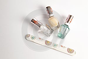 Three bottles of clear nail polish with emery board on white surface