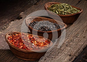 Three bowls with spices over wooden background.