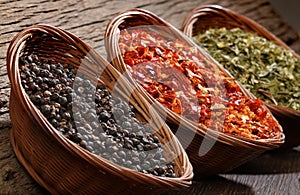 Three bowls with spices over wooden background.