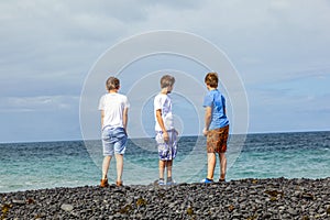 Three boys have fun at the black volcanic beach