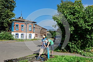 Three boys playing with a public water tap. Suzdal, Russia