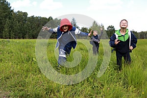 Three boys running across field