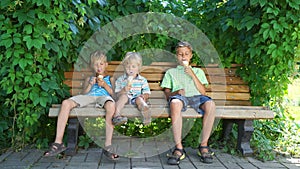Three boys sitting in park and eating ice cream