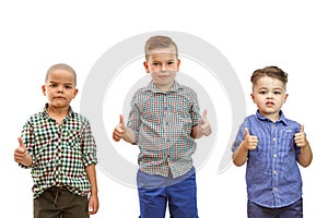 Three boys are standing together on the white background and hold their thumbs up