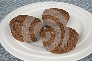 Three bran muffins on white plate