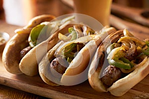 Three bratwurst sausages with grilled onions and bell peppers photo