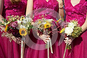 Three bridesmaids in lilac lace dresses with bouquets of fresh flowers, selective focus