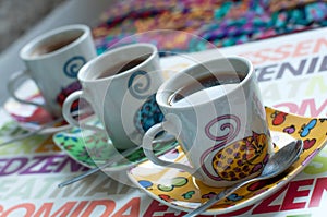 Three bright coffee cups with hot espresso on a colorful surface