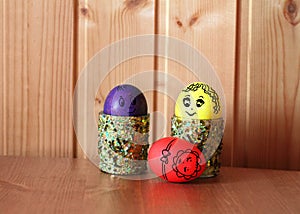 Three bright easter eggs with drawn eyes represent family