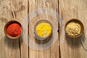 Three bright spices cayenne, turmeric, ginger in a wooden bowl on a table. Top view