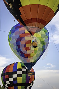 Three brightly colored hot air balloons hover tethered above the ground.