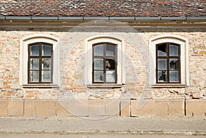 Three broken windows in a wall of a damaged building