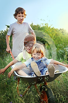 Three brother playing in the plane using a garden carts