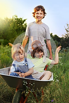 Three brother playing in the plane using a garden carts