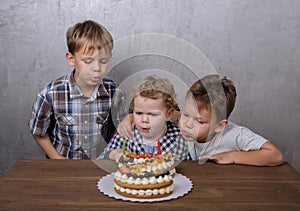 Three brothers blow out candles on birthday cake