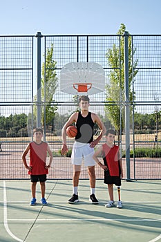 Three brothers looking at camera with a basketball, one has a leg prosthesis.
