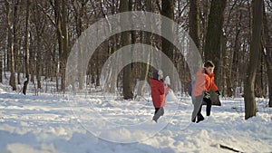 Three brothers play snowballs in winter park, slow motion
