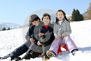 Three brothers on the sled in the snow in winter