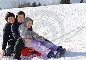 Three brothers on the sled in the snow in winter