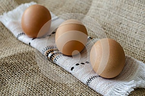 Three brown chicken eggs on burlap